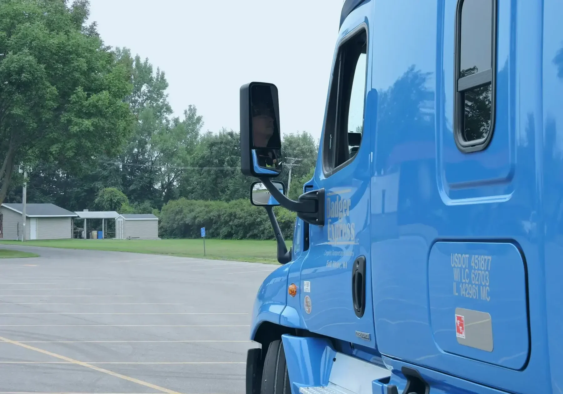 Blue semi-truck near trees and buildings