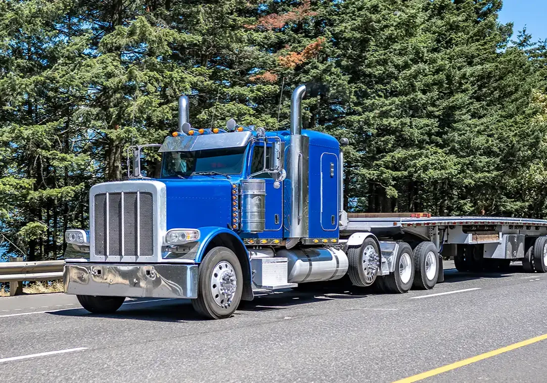 Blue semi truck with empty flatbed trailer