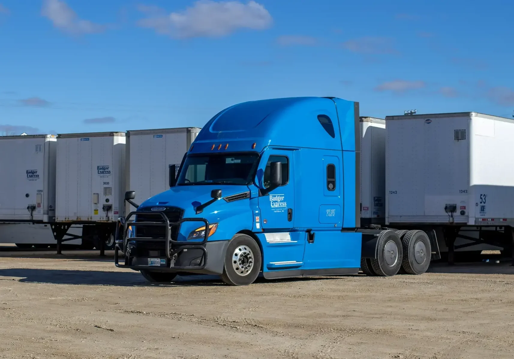 Blue semi truck parked near white trailers